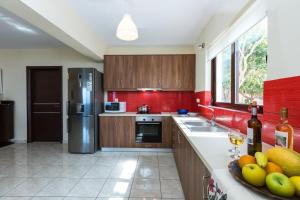 cocina con paredes rojas y armarios de madera en Kalathas Sunset Villa, en Kalathas