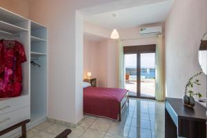 1 dormitorio con 1 cama y puerta a un balcón en Kalathas Sunset Villa, en Kalathas