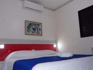 a bedroom with two beds and a flat screen tv at Hotel Rota do Pantanal in Presidente Prudente