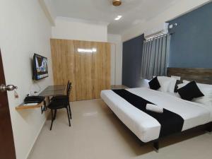 a bedroom with a large bed and a desk in it at Super Collection O Rio Kondapur Near Rahavendra Colony in Hyderabad +63 photos
