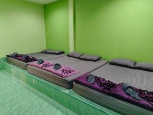 two beds in a room with green walls at Pooma Resort in Chao Lao Beach