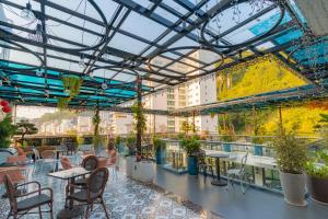 a rooftop patio with tables and chairs and plants at Roza Luxury Hotel Cat Ba - Pool & Rooftop in Cat Ba