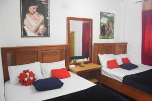 a bedroom with two beds with red and blue pillows at Ellagama Village Bungalow in Diyatalawa