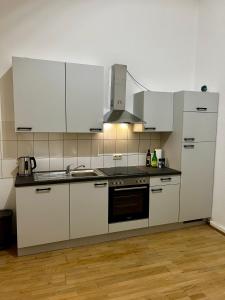 a kitchen with white cabinets and a stove top oven at LaBed - Wohnen direkt an der Drosselgasse, stilvolle Ferienwohnung mit Rheinblick in Rüdesheim am Rhein +22 photos