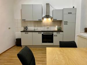 a kitchen with white cabinets and a table with chairs at LaBed - Wohnen direkt an der Drosselgasse, stilvolle Ferienwohnung mit Rheinblick in Rüdesheim am Rhein