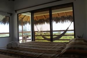 una camera da letto con un letto e una finestra con un'amaca di Hosteria Guachapeli a Las Tunas