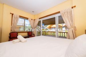 a bedroom with a bed and a large window at 4 Bedroom Log Cabin in Camp John Hay Baguio in Baguio