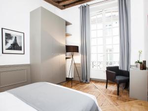ein Schlafzimmer mit einem Bett, einem Stuhl und einem Fenster in der Unterkunft LivinParis - Luxury 2 Bedrooms Le Marais I in Paris