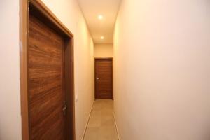 un couloir vide avec une porte en bois et un couloir dans l'établissement Qubenest Elite Manyata Tech Park, à Bangalore 1 autre photo