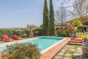 a swimming pool with two red chairs in a yard at Fienile Da Primo in San Giovanni Valdarno