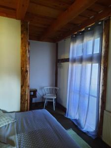 a bedroom with a bed and a window with a chair at Cabana Belis Dealu Negru in Beliş
