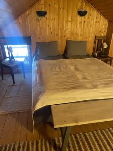 a bed in a room with a wooden wall at Majatalo Wanha-Pirtti in Iitti