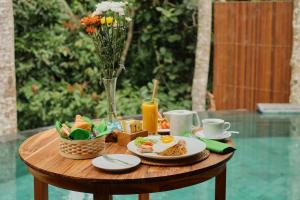 a table with breakfast foods and drinks on it at Elitya Ubud Villa in Ubud