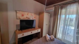 a bedroom with a tv on a dresser with a window at Teta's Holiday Home in Melíkia +16 photos