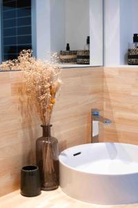 une salle de bain avec un lavabo blanc et un vase avec des fleurs dans l'établissement Le Bonamour - Élégance et sérénité entre plage et port, à Capbreton