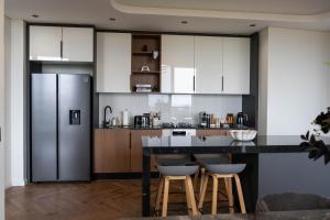 a kitchen with white cabinets and a counter with stools at Prada Penthouse at On Park Century City in Cape Town