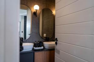 a bathroom with two sinks and two mirrors at Prada Penthouse at On Park Century City in Cape Town +38 photos