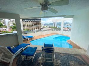 a large swimming pool with chairs and a ceiling fan at Hotel Suites Jazmín Acapulco in Acapulco