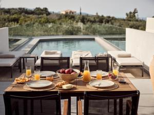 PsarouPιgeon Nest Villa的一张桌子,上面放着一碗水果和饮料,还有一个游泳池