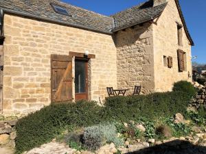 an old stone building with a wooden door and a bench at Petite maison du causse in Salles-la-Source