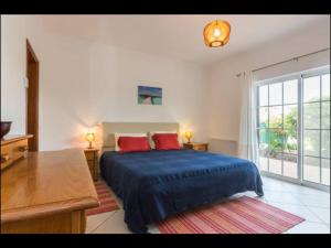 een slaapkamer met een blauw bed en een groot raam bij Villa Vilamar in Porches +39 foto's
