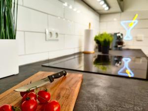a cutting board with a knife and tomatoes on a counter at Modernes Loft-Erlebnis mit Fitnessbereich & Heimkino in Magdeburg +15 photos