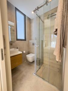 a bathroom with a shower and a toilet and a sink at Malberry Park 102 - Modern Apt with Shared Heated Pool, Sauna, Gym, Jacuzzi in Paphos City
