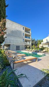 a swimming pool with chaise lounges in front of a building at Malberry Park 102 - Modern Apt with Shared Heated Pool, Sauna, Gym, Jacuzzi in Paphos City