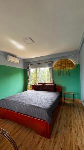 ロン島にあるRoomy Guesthouseの緑の壁のベッドルーム1室(窓付)