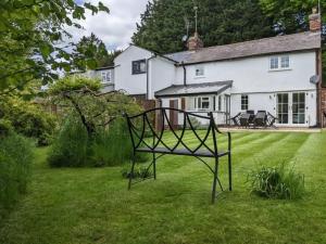 a bench sitting in the grass in front of a house at Beautifully refurbished 3 bedroom cottage in Ashdon