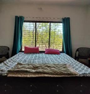 a bedroom with a large bed with two pink pillows at Jungle home stay in Devrukh