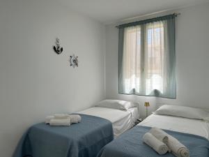 two beds in a white room with towels on them at Sunlands 50 meters from the sandy beach with wifi in Avola