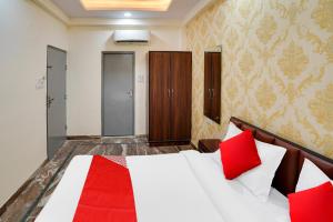 Un dormitorio con una cama blanca con almohadas rojas. en Hotel O Uday, en Jaipur