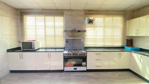 a kitchen with white cabinets and a stove top oven at Private Cottage in Sharjah