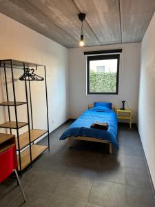a bedroom with a blue bed and a window at Stay Every Day in Maldegem