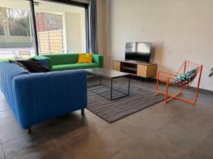 a living room with a blue couch and a tv at Stay Every Day in Maldegem