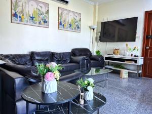 una sala de estar con un sofá de cuero negro y mesas. en 2 BR villa with private swimming pool and jacuzzi 350m from beach, en Pattaya South
