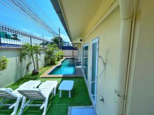 balcón con sillas blancas y piscina en 2 BR villa with private swimming pool and jacuzzi 350m from beach, en Pattaya South