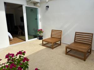 two wooden chairs sitting on a porch with flowers at Laloon Guesthouse in Hat Yai +24 photos