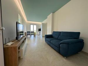a living room with a blue couch and a tv at Bed&BikeRome GALERIA ANTICA in Santa Maria di Galeria