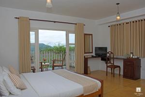 a bedroom with a bed and a desk with a computer at Villa Perpetua in Bandarawela