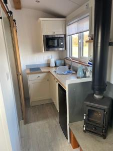 梅奈布里奇Cybi, Modern Shepherds Hut with Games Room Access的一间小厨房,位于一个小房子内,配有炉灶