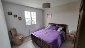 a bedroom with a bed with purple sheets and a chair at Maison en bord de Rance in Taden