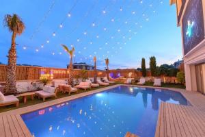 a swimming pool with chaise lounge chairs and palm trees at Mistral Alaçatı Hotel in Çeşme