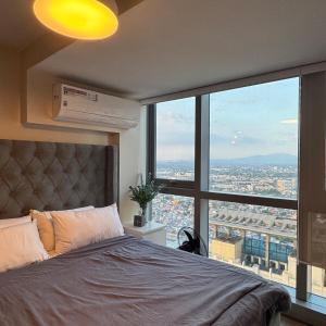 a bedroom with a bed and a large window at Elegant 1BR with Great View, Panoramic Pool Near Ortigas CBD - 24 in Manila