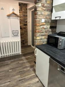 a kitchen with white cabinets and a brick wall at Cherry Street Apartment in Wolsztyn