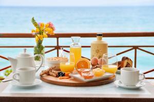 a tray of breakfast foods and orange juice on a table at Pharos Rooms in Ilia +35 photos