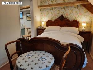 a bedroom with a large bed with a wooden headboard at Cotswold Cottage B&B - 5 Minutes Walk to Village Pub in Luckington