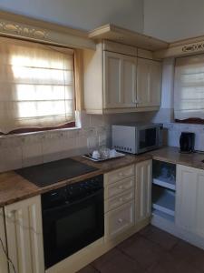 una cucina con mobili bianchi e un forno a piano cottura di Buchan Estate and Self Catering a Città del Capo