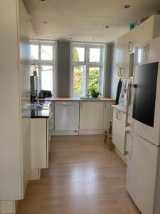 a kitchen with white cabinets and a wooden floor at Charmerende byhus - tæt på alt! in Svendborg